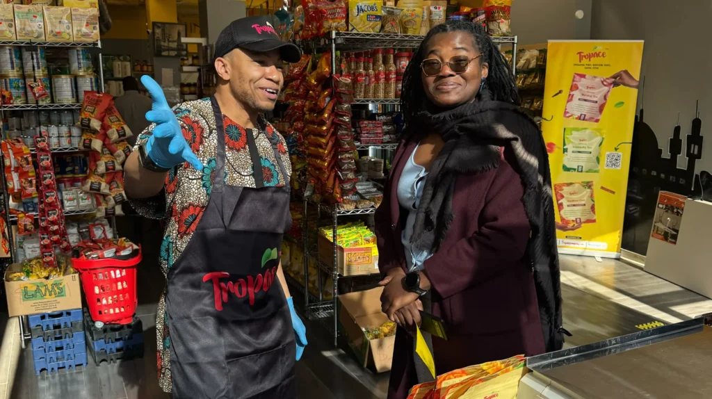 Mamud Dako, founder of Tropace, standing behind a demo table inside La’Afrique Market with Tropace Tea products on display.
