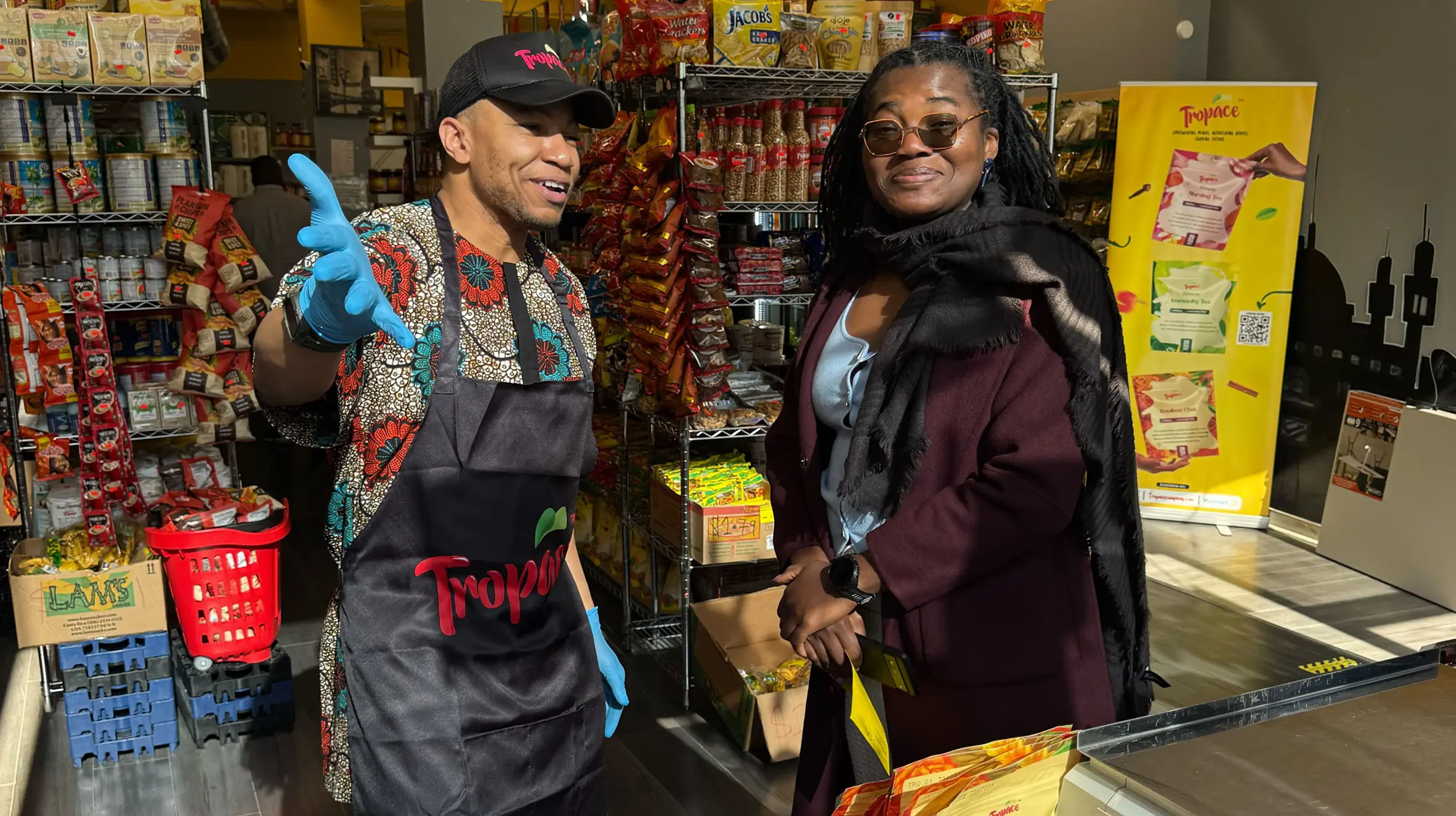 Mamud Dako, founder of Tropace, standing behind a demo table inside La’Afrique Market with Tropace Tea products on display.